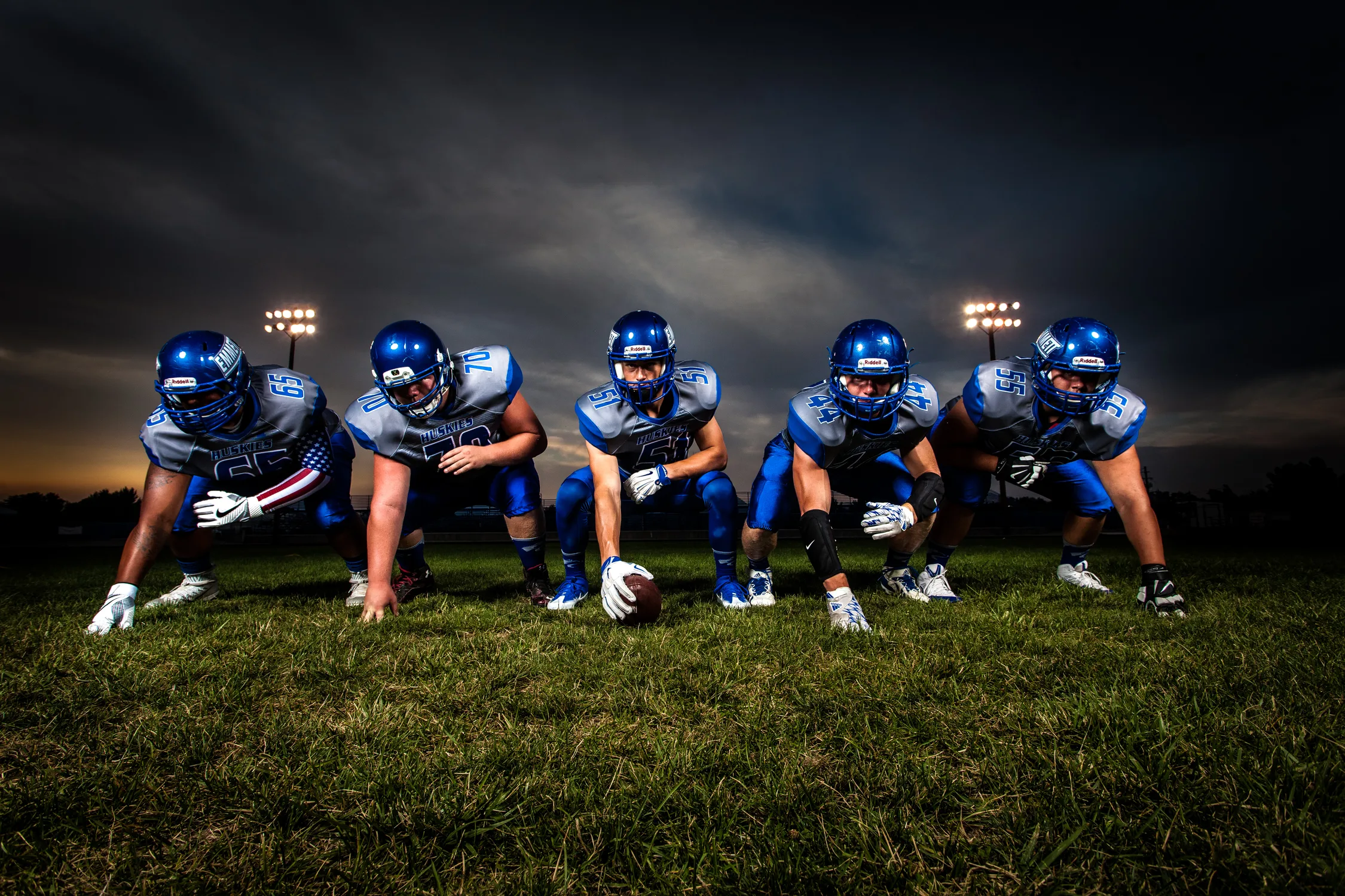 team of football players in blue jerseys under grey sky